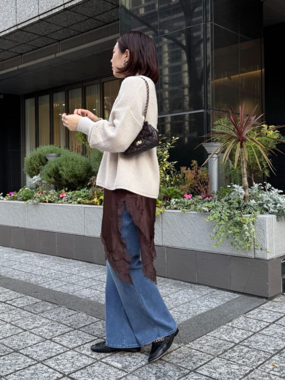 ブラウン系のキャミソール、ブルー系のデニムパンツ、ホワイト系のニット/セーターを着用したレディースの冬コーディネートの4枚目の写真