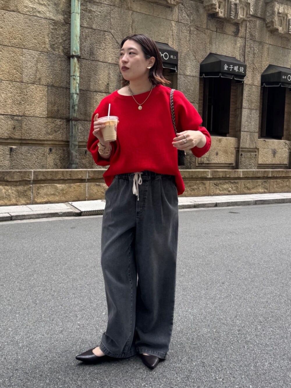 ブラック系のデニムパンツ、ブラウン系のショルダーバッグ、レッド系のニット/セーターを着用したレディースの夏コーディネートの3枚目の写真