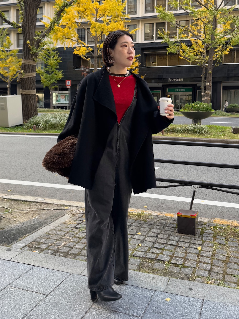 ブラック系のつなぎ/オールインワン、レッド系のニット/セーター、ブラック系のその他アウターを着用したレディースの冬コーディネートの4枚目の写真