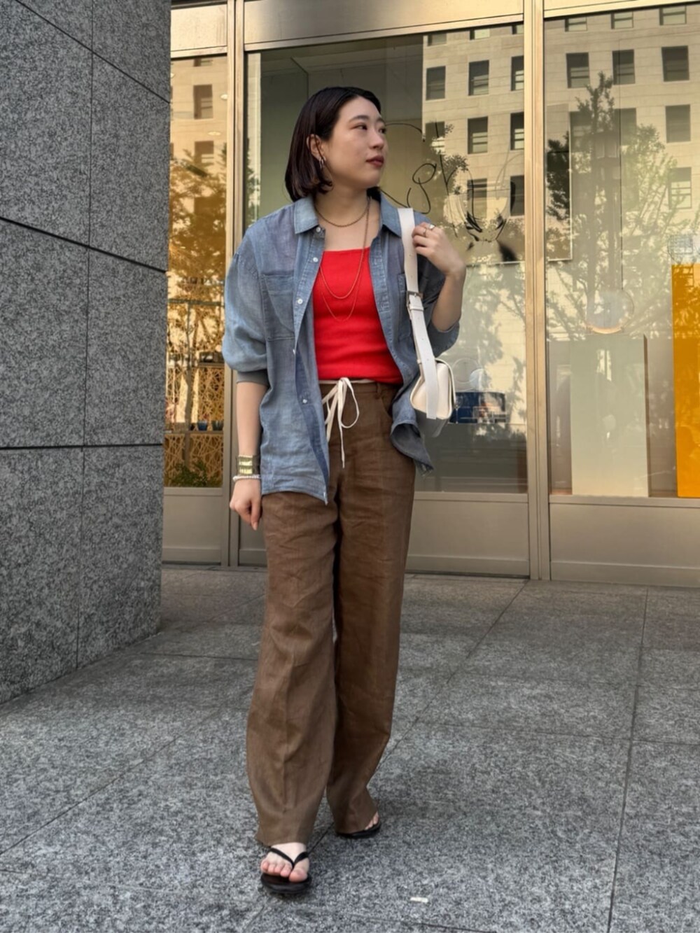 ホワイト系のショルダーバッグ、ブルー系のシャツ/ブラウス、オレンジ系のタンクトップを着用したレディースの春コーディネートの3枚目の写真