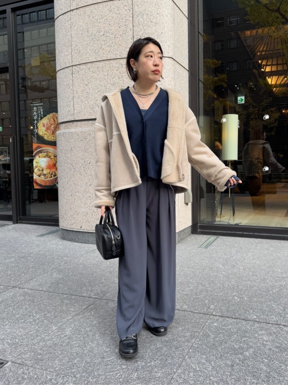 グレー系のスラックス、ブラック系のショルダーバッグ、ベージュ系のその他アウターを着用したレディースの冬コーディネートの7枚目の写真