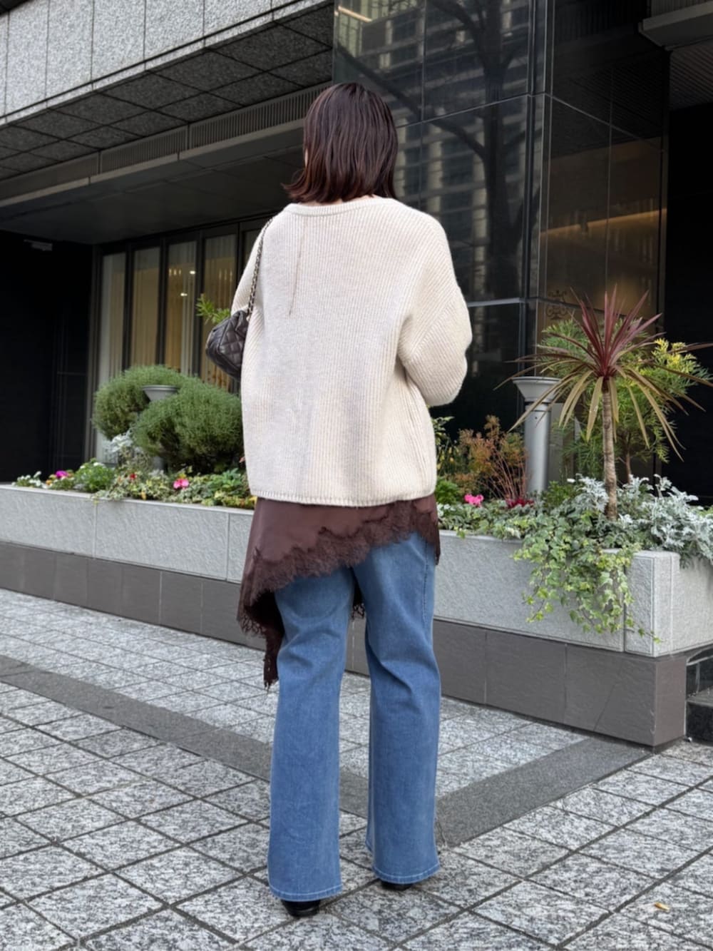 ブラウン系のキャミソール、ブルー系のデニムパンツ、ホワイト系のニット/セーターを着用したレディースの冬コーディネートの2枚目の写真