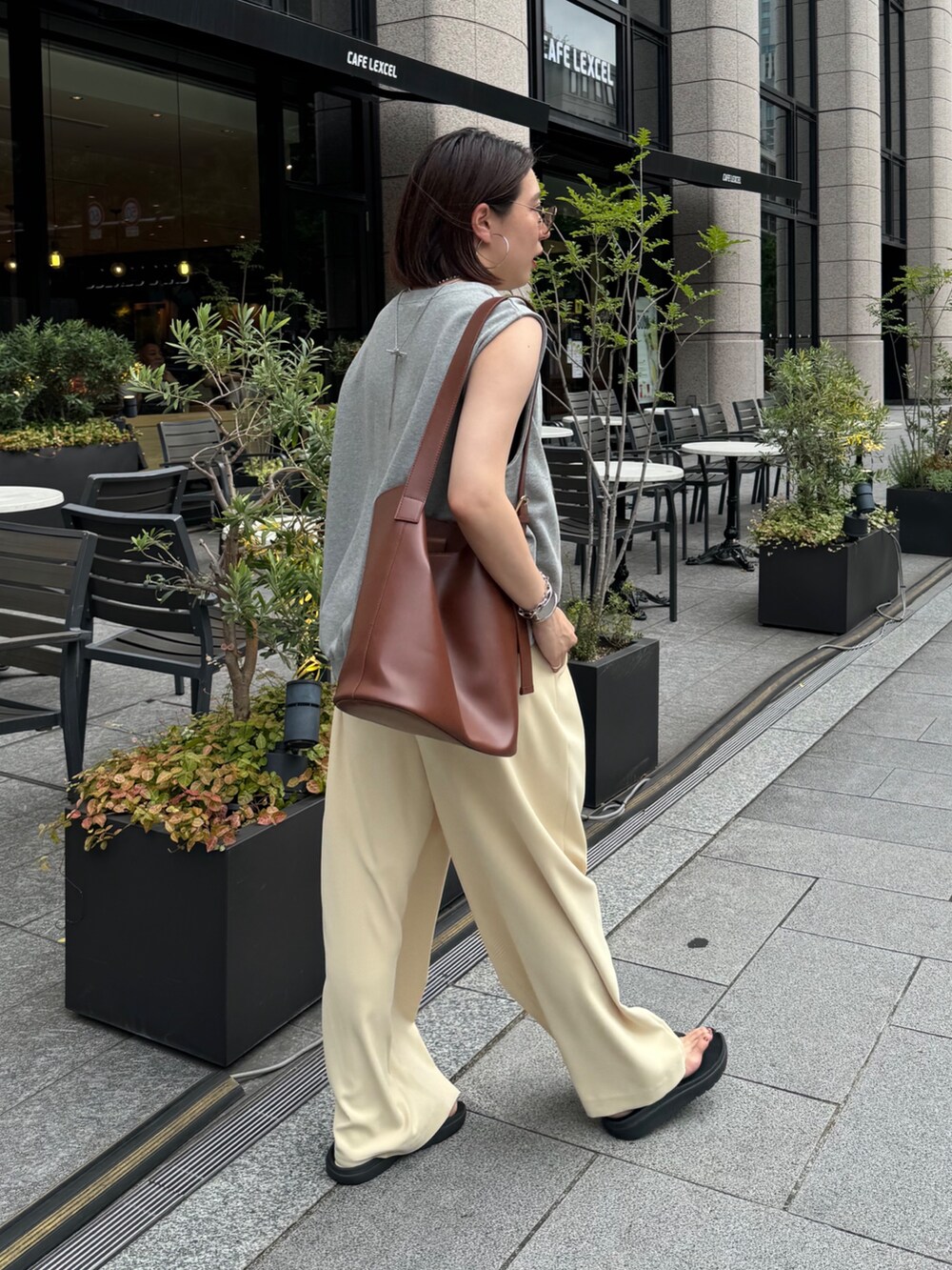 イエロー系のスラックス、グレー系のスウェット、シルバー系のベルトを着用したレディースの夏コーディネートの2枚目の写真