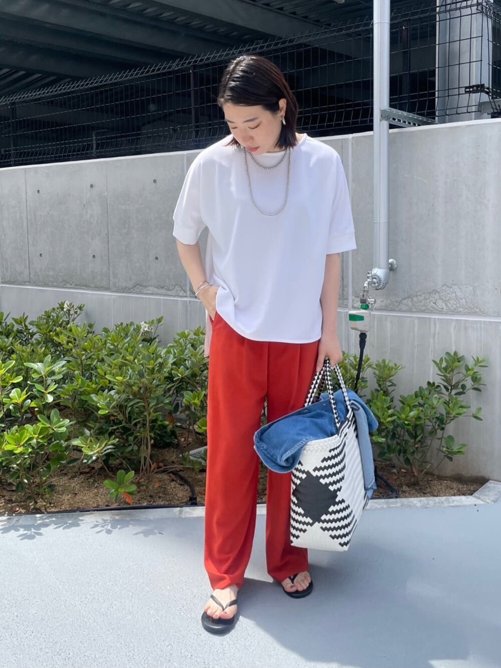ホワイト系のシャツ/ブラウス、オレンジ系のスラックス、ホワイト系のかごバッグを着用したレディースの夏コーディネートの7枚目の写真