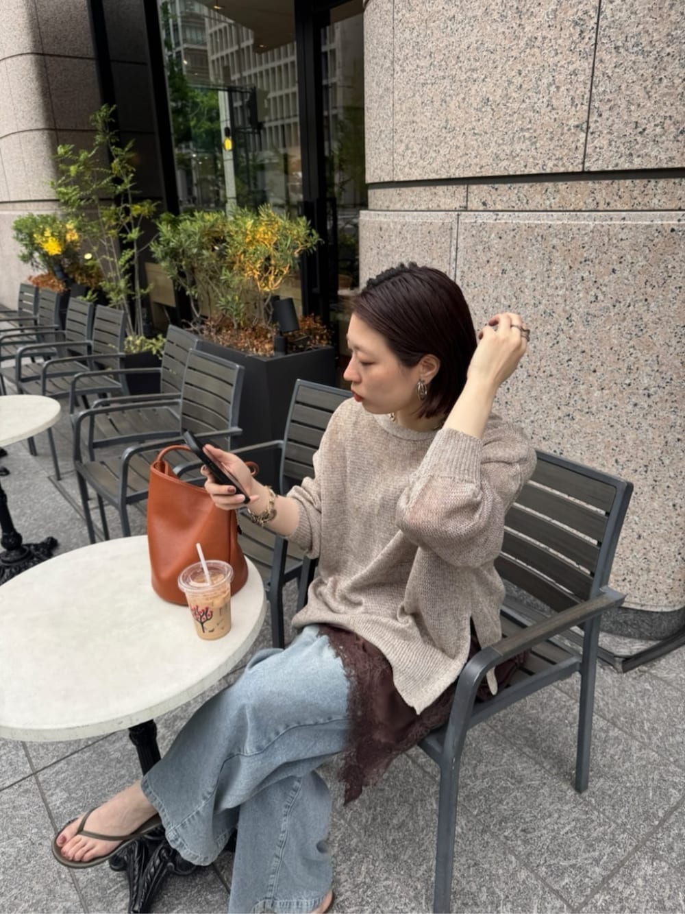 ブルー系のデニムパンツ、ブラウン系のキャミソール、ベージュ系のカーディガン/ボレロを着用したレディースの春コーディネートの6枚目の写真