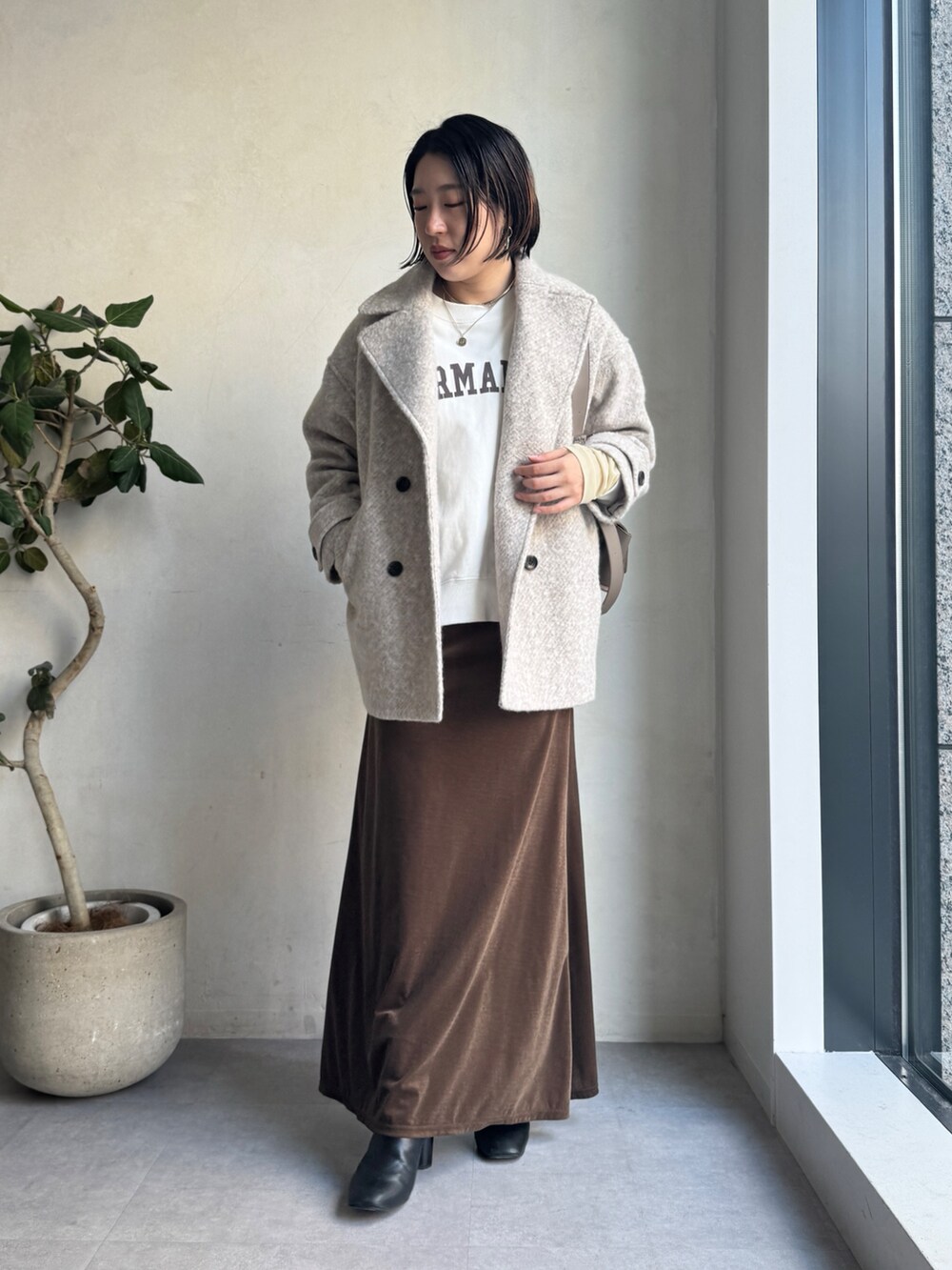 ベージュ系のその他アウター、ブラウン系のスカート、ホワイト系のTシャツ/カットソーを着用したレディースの冬コーディネートの2枚目の写真