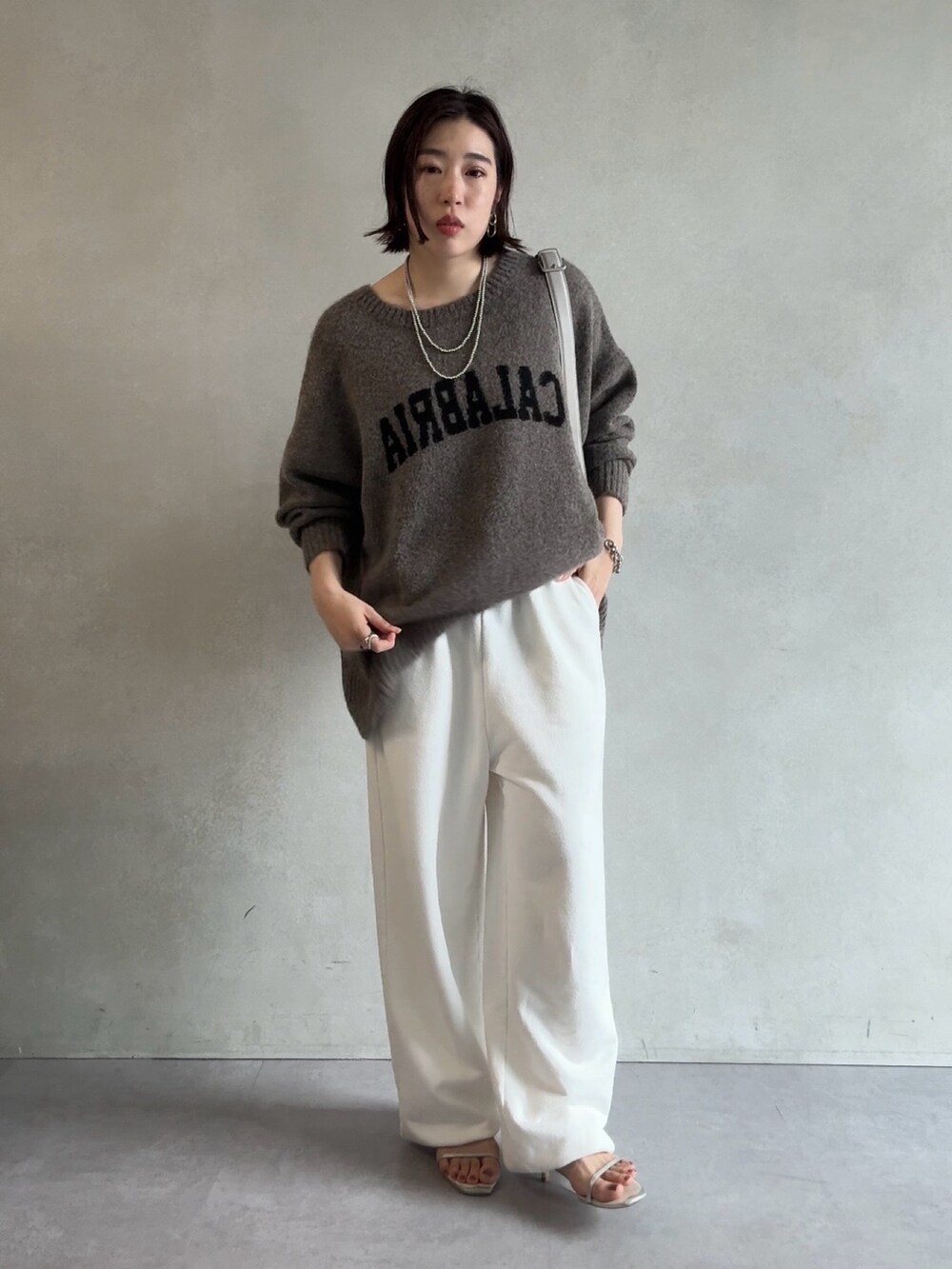 ベージュ系のニット/セーター、ホワイト系のスウェットパンツ、グレー系のショルダーバッグを着用したレディースの秋コーディネートの2枚目の写真