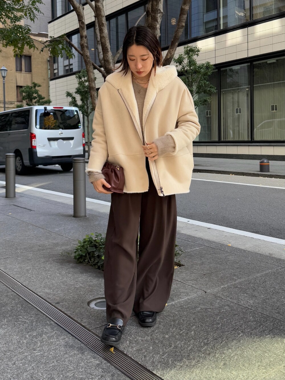 ブラウン系のスラックス、ブラウン系のニット/セーター、ホワイト系のその他アウターを着用したレディースの冬コーディネートの2枚目の写真