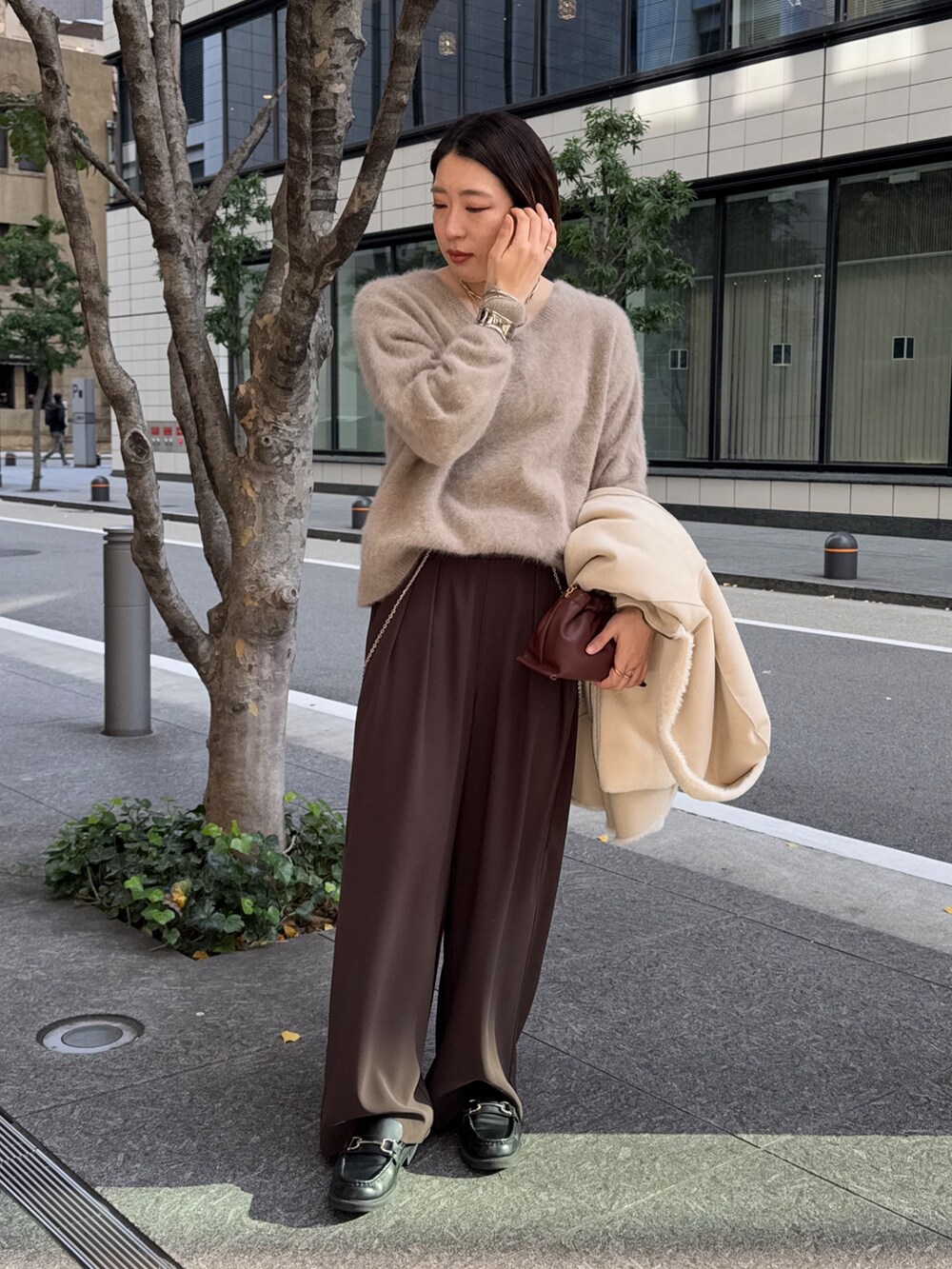 ブラウン系のスラックス、ブラウン系のニット/セーター、ホワイト系のその他アウターを着用したレディースの冬コーディネートの7枚目の写真