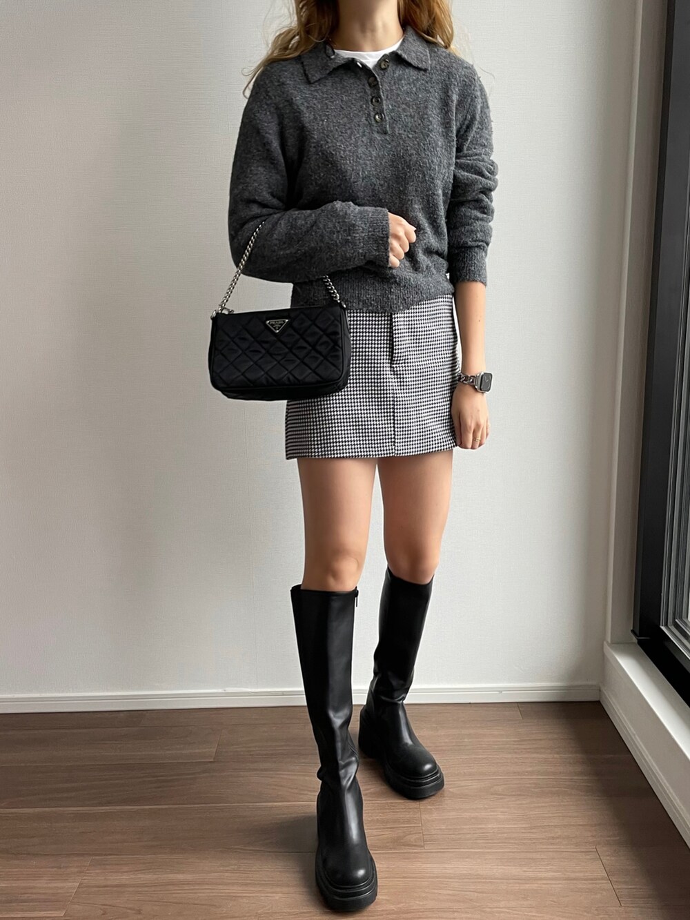 ブラック系のスカート、ブラック系のブーツ、ブラック系のハンドバッグを着用したレディースの秋コーディネートの4枚目の写真