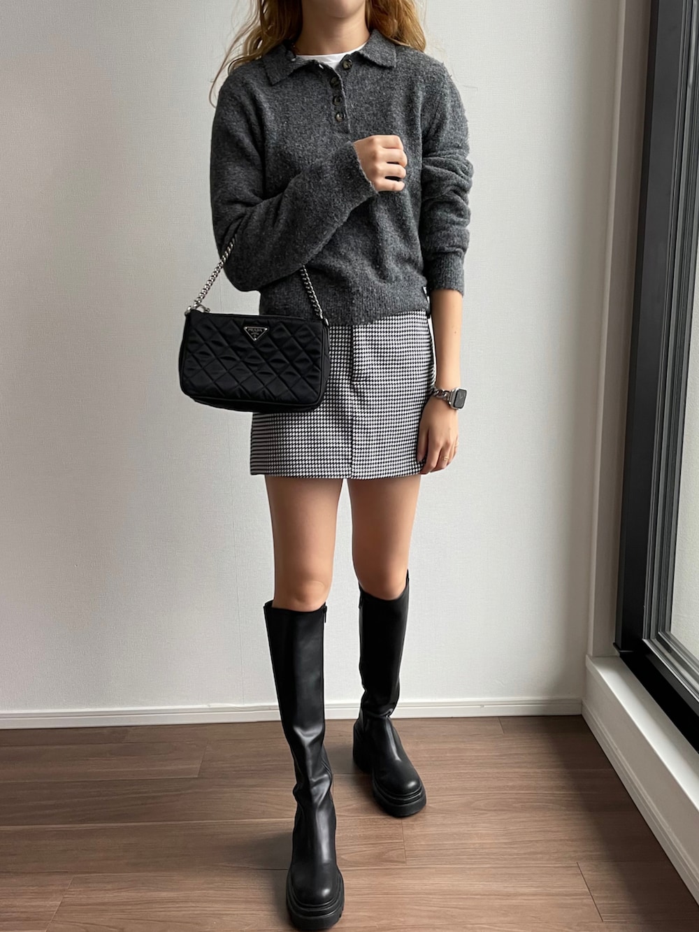 ブラック系のスカート、ブラック系のブーツ、ブラック系のハンドバッグを着用したレディースの秋コーディネートの3枚目の写真