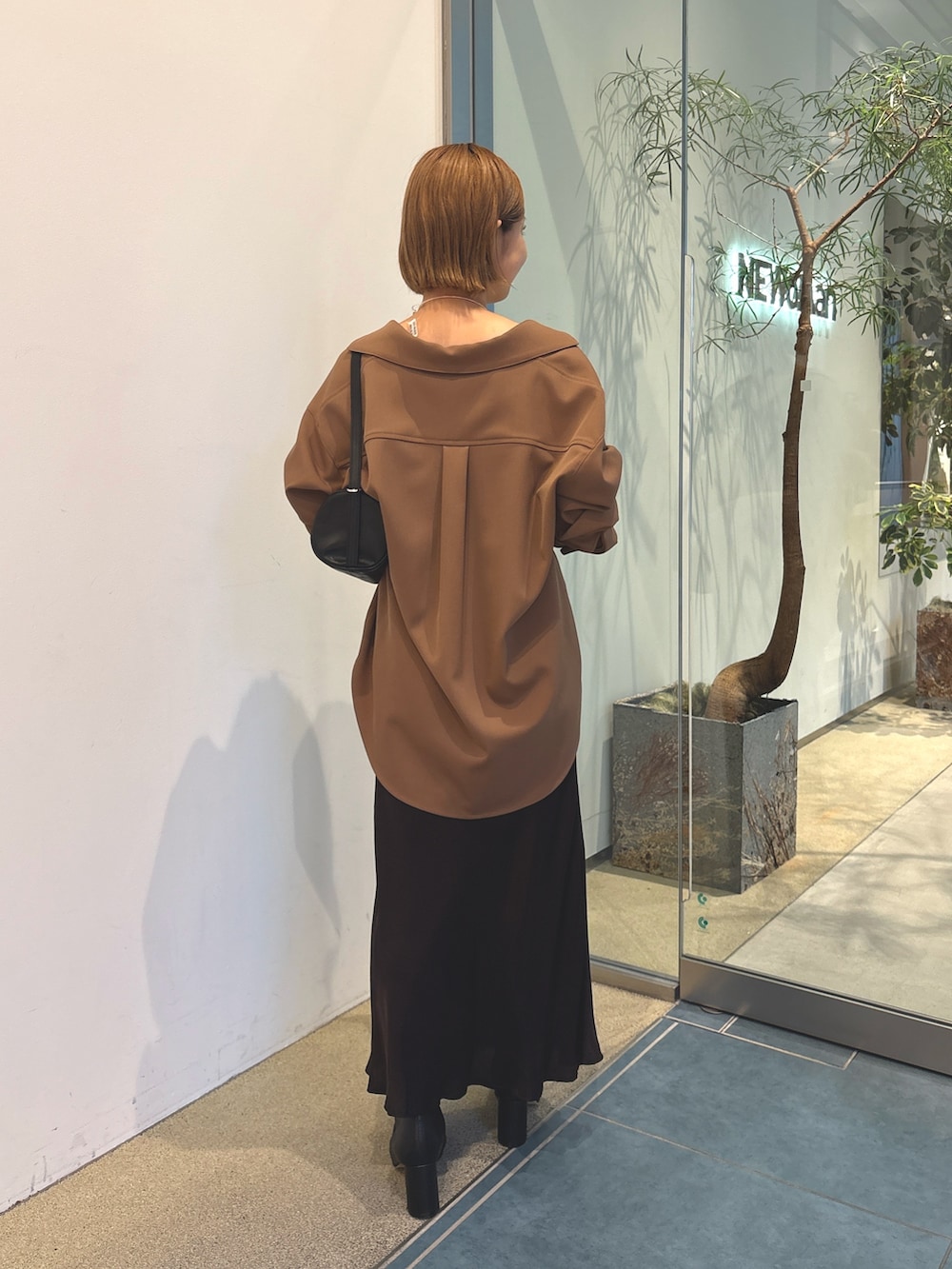 ブラウン系のスカート、ブラック系のショルダーバッグ、ホワイト系のキャミソールを着用したレディースの秋コーディネートの5枚目の写真