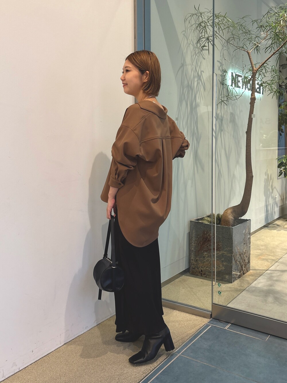 ブラウン系のスカート、ブラック系のショルダーバッグ、ホワイト系のキャミソールを着用したレディースの秋コーディネートの4枚目の写真