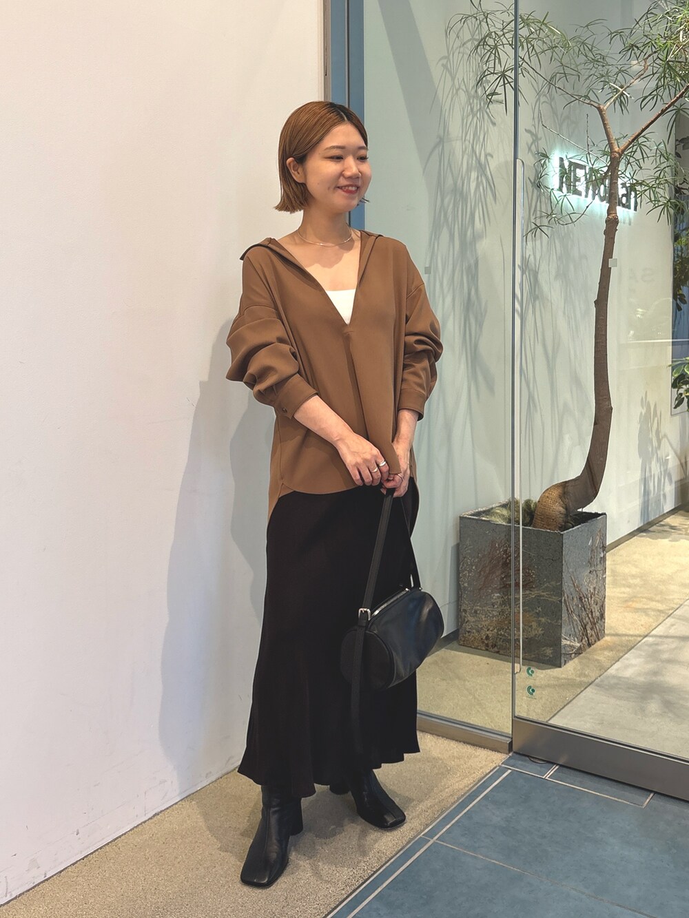 ブラウン系のスカート、ブラック系のショルダーバッグ、ホワイト系のキャミソールを着用したレディースの秋コーディネートの3枚目の写真