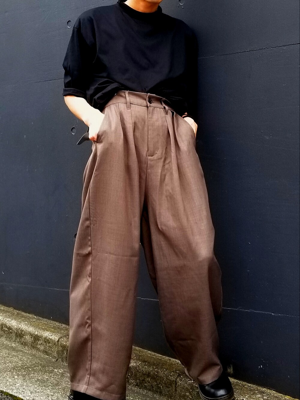 ブラック系のTシャツ/カットソー、ブラック系のローファー、ブラウン系のスラックスを着用したメンズの夏コーディネートの2枚目の写真