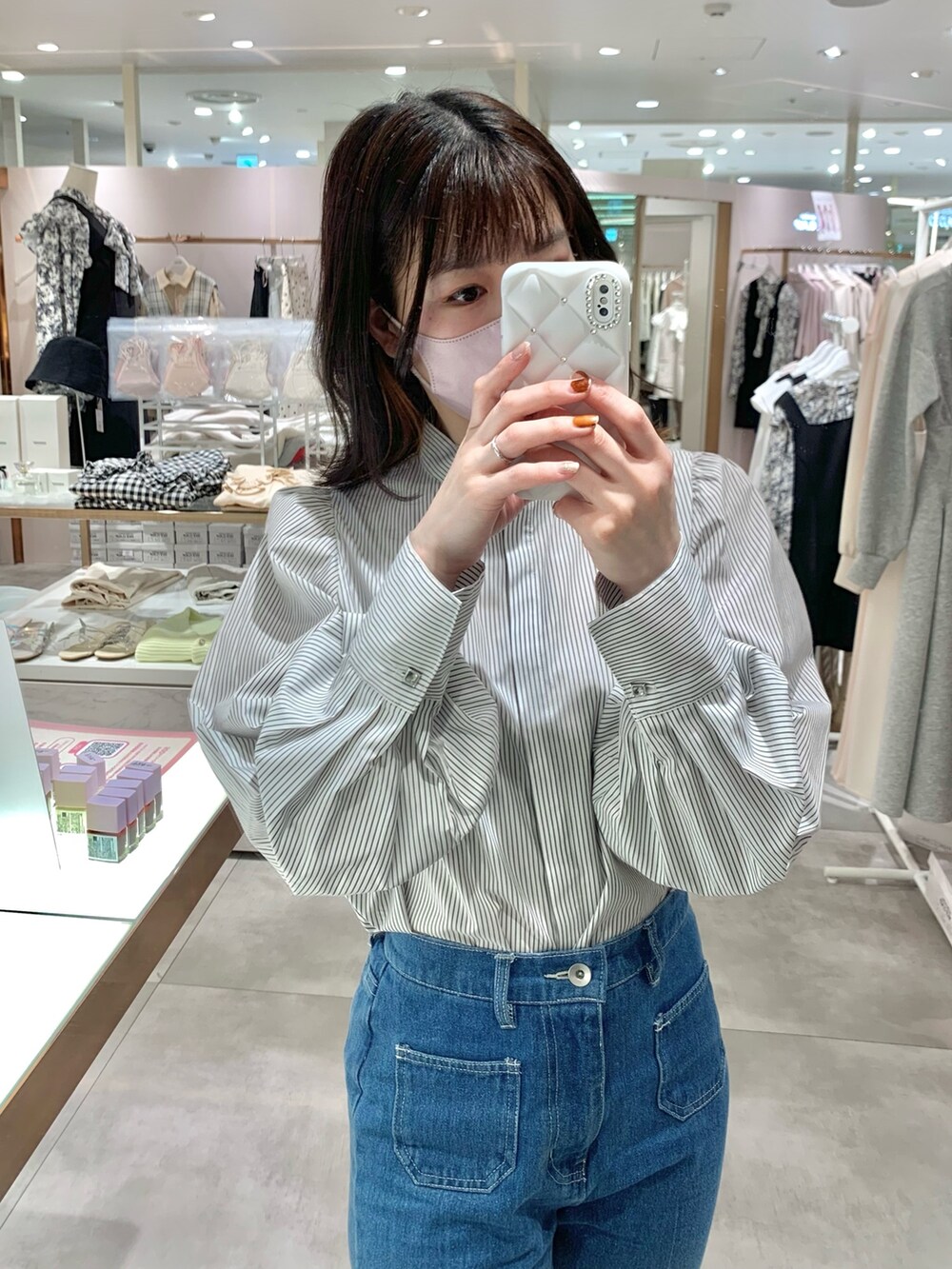ベージュ系のトレンチコート、グレー系のブーツ、ブルー系のデニムパンツを着用したレディースの春コーディネートの9枚目の写真