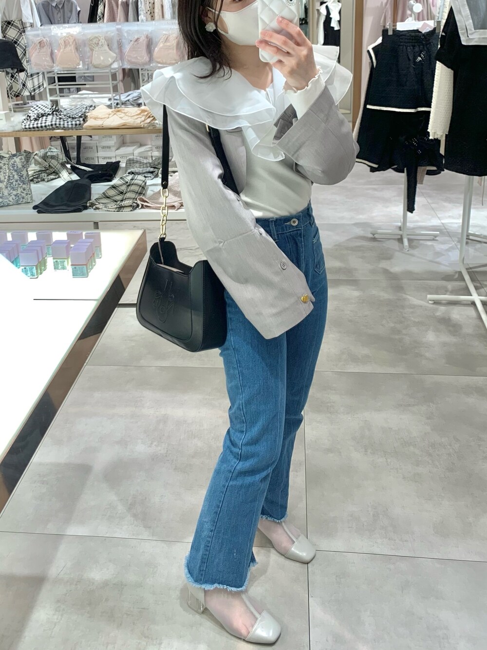 イエロー系のショルダーバッグ、ブルー系のデニムパンツ、グレー系のブーツを着用したレディースの春コーディネートの2枚目の写真
