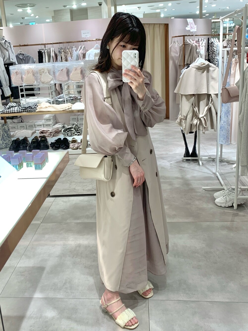 ベージュ系のトレンチコート、ホワイト系のサンダル、ホワイト系のボディバッグ/ウエストポーチを着用したレディースの春コーディネートの3枚目の写真