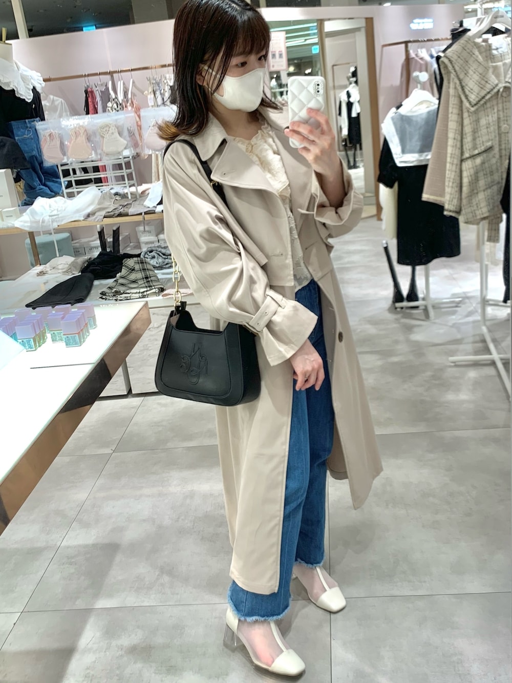 ベージュ系のトレンチコート、ブラック系のショルダーバッグ、ブルー系のデニムパンツを着用したレディースの春コーディネートの2枚目の写真