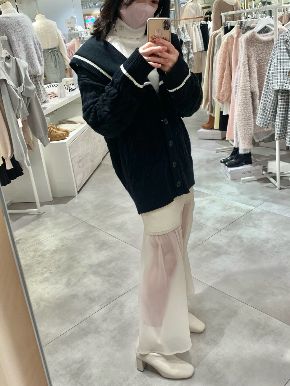 ホワイト系のTシャツ/カットソー、ブラック系のカーディガン/ボレロ、ホワイト系のスカートを着用したレディースの冬コーディネートの3枚目の写真