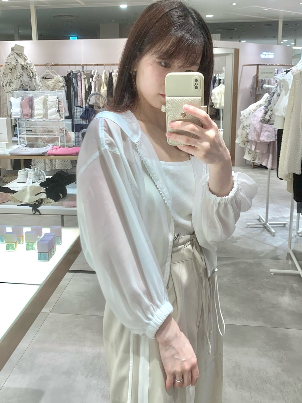 ベージュ系のスラックス、ホワイト系のサンダル、ホワイト系のマウンテンパーカーを着用したレディースの春コーディネートの6枚目の写真