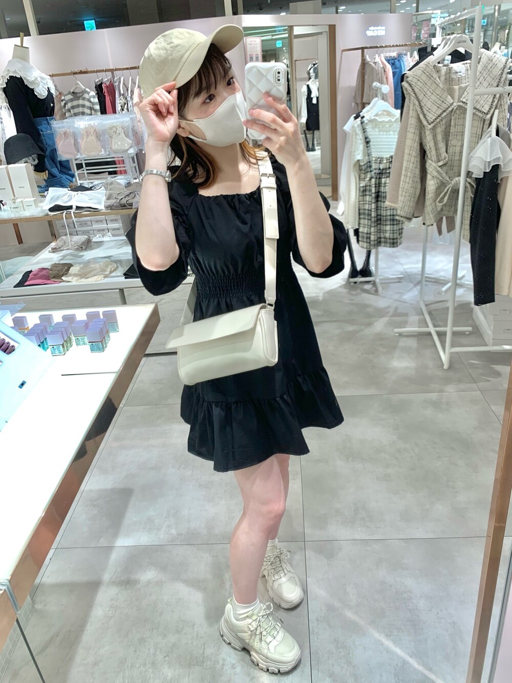 ブラック系のチュニック、ホワイト系のボディバッグ/ウエストポーチ、ブルー系のデニムパンツを着用したレディースの春コーディネートの6枚目の写真