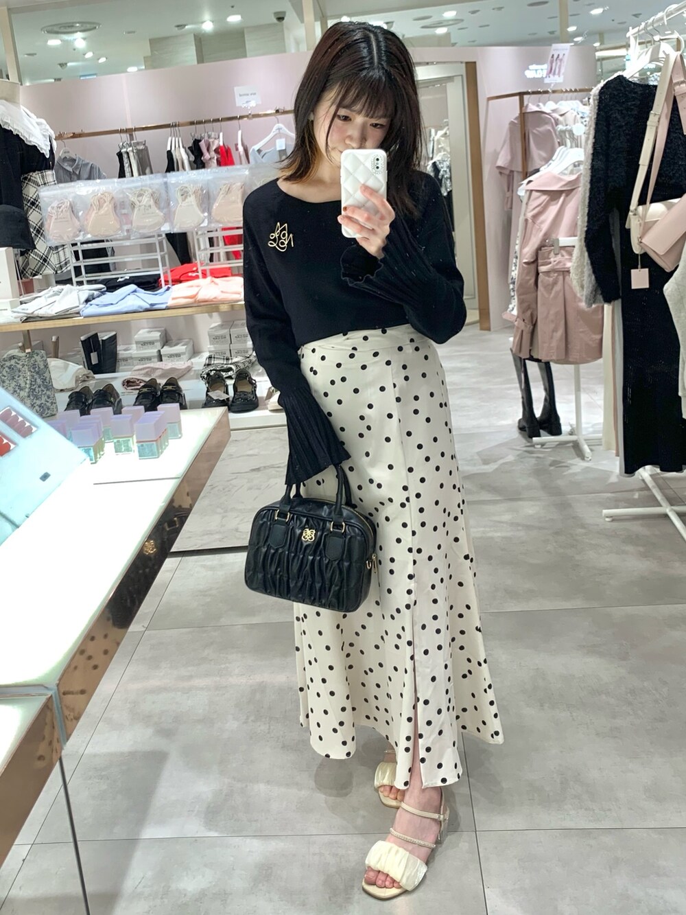 ベージュ系のトレンチコート、ホワイト系のニット/セーター、グリーン系のスカートを着用したレディースの春コーディネートの4枚目の写真