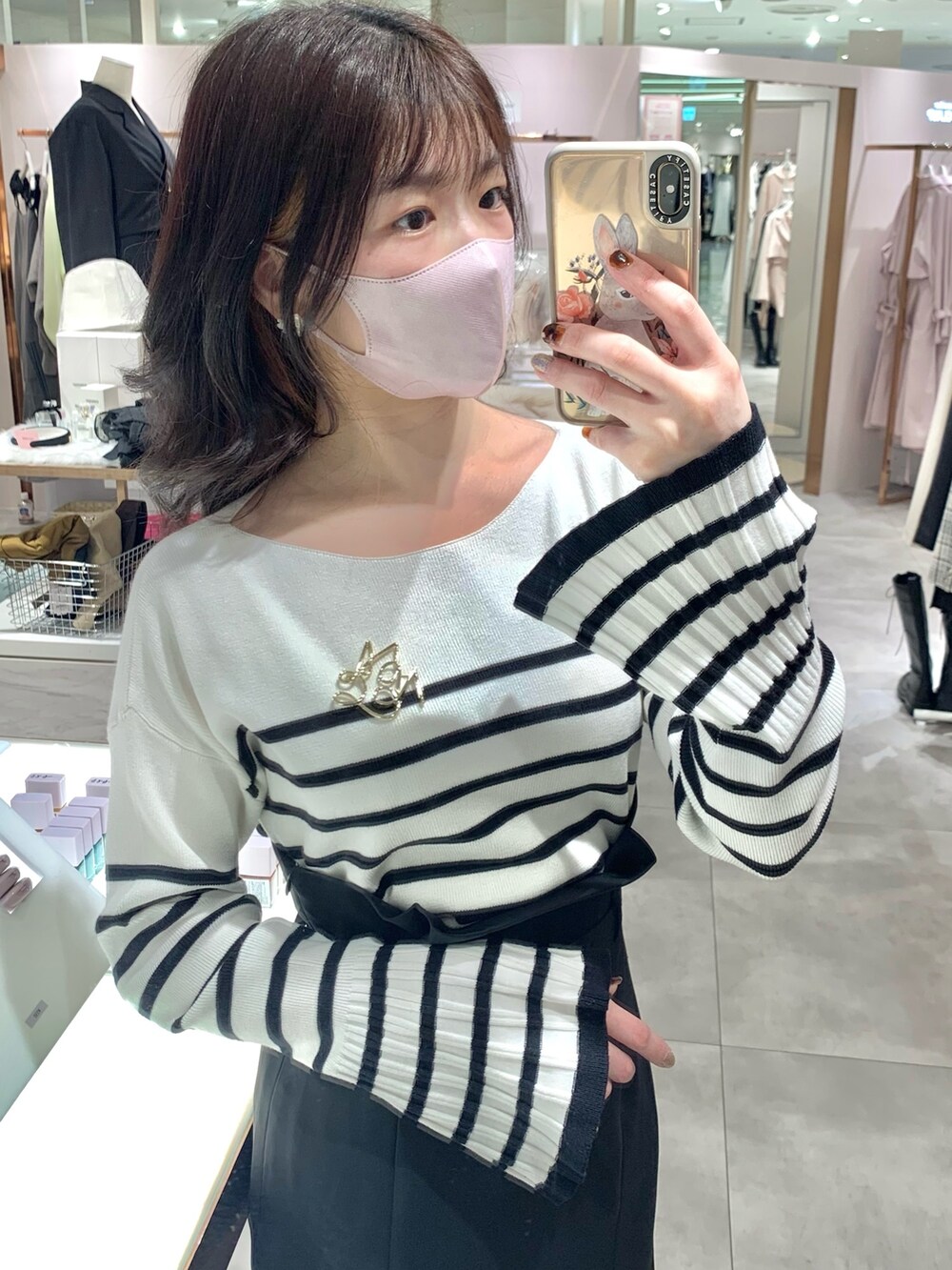 ホワイト系のトートバッグ、ブラック系のスカート、ホワイト系のニット/セーターを着用したレディースの春コーディネートの2枚目の写真