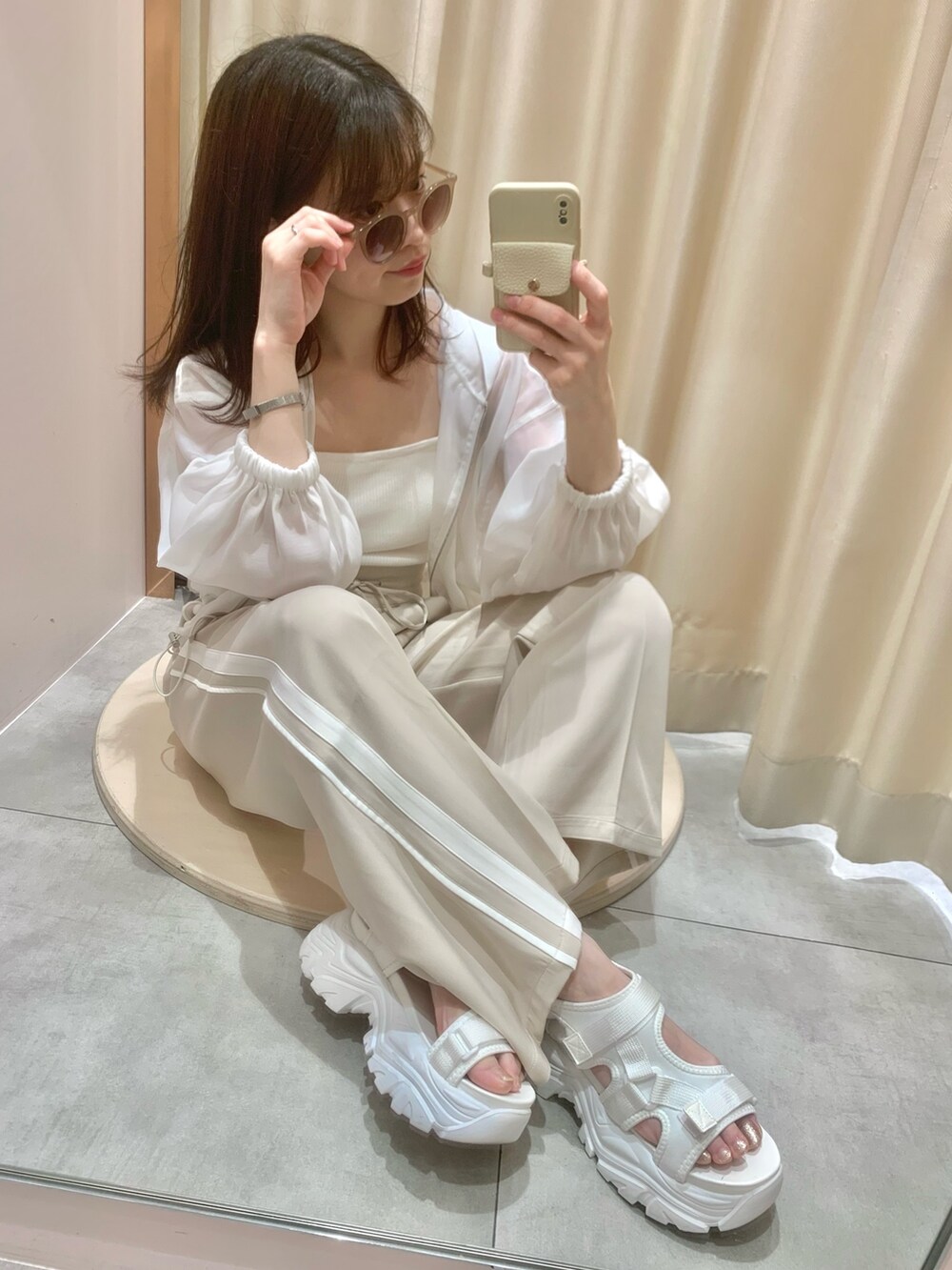 ベージュ系のスラックス、ホワイト系のサンダル、ホワイト系のマウンテンパーカーを着用したレディースの春コーディネートの5枚目の写真