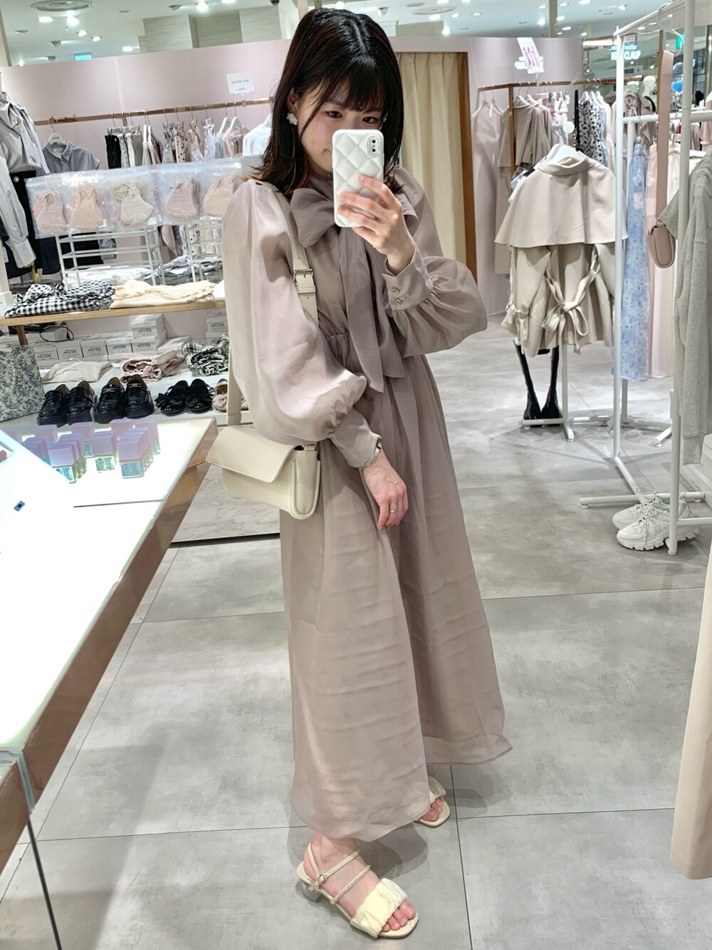 ベージュ系のトレンチコート、ホワイト系のサンダル、ホワイト系のボディバッグ/ウエストポーチを着用したレディースの春コーディネートの8枚目の写真