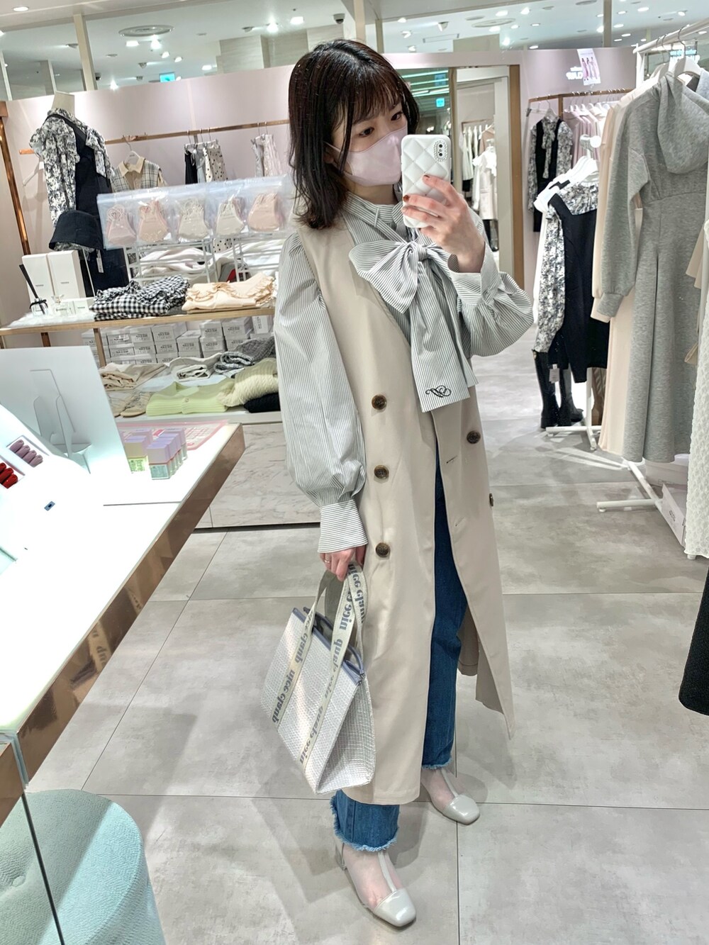 ベージュ系のトレンチコート、グレー系のブーツ、ブルー系のデニムパンツを着用したレディースの春コーディネートの5枚目の写真