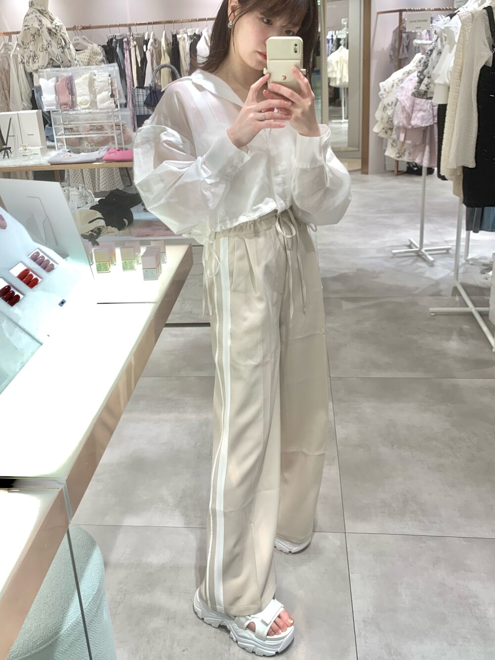 ベージュ系のスラックス、ホワイト系のサンダル、ホワイト系のマウンテンパーカーを着用したレディースの春コーディネートの10枚目の写真