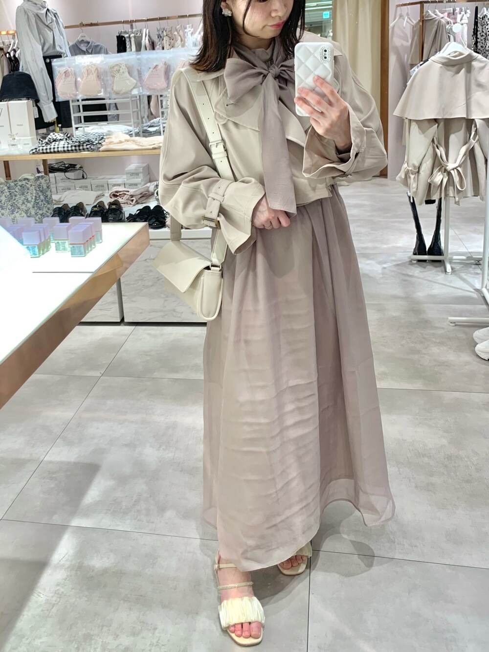 ベージュ系のトレンチコート、ホワイト系のサンダル、ホワイト系のボディバッグ/ウエストポーチを着用したレディースの春コーディネートの5枚目の写真