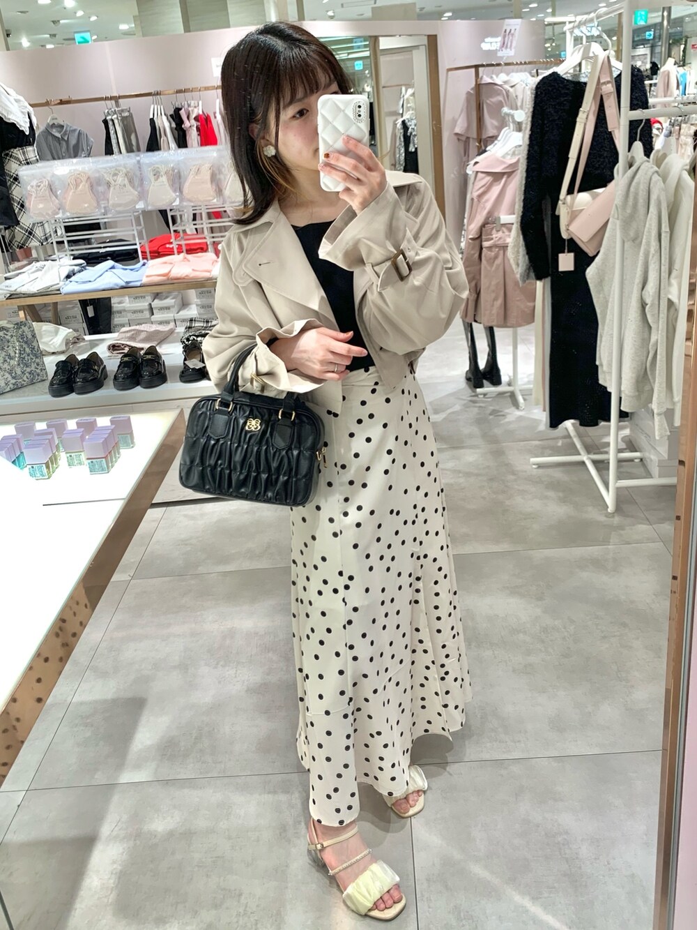 ベージュ系のトレンチコート、ホワイト系のニット/セーター、グリーン系のスカートを着用したレディースの春コーディネートの2枚目の写真