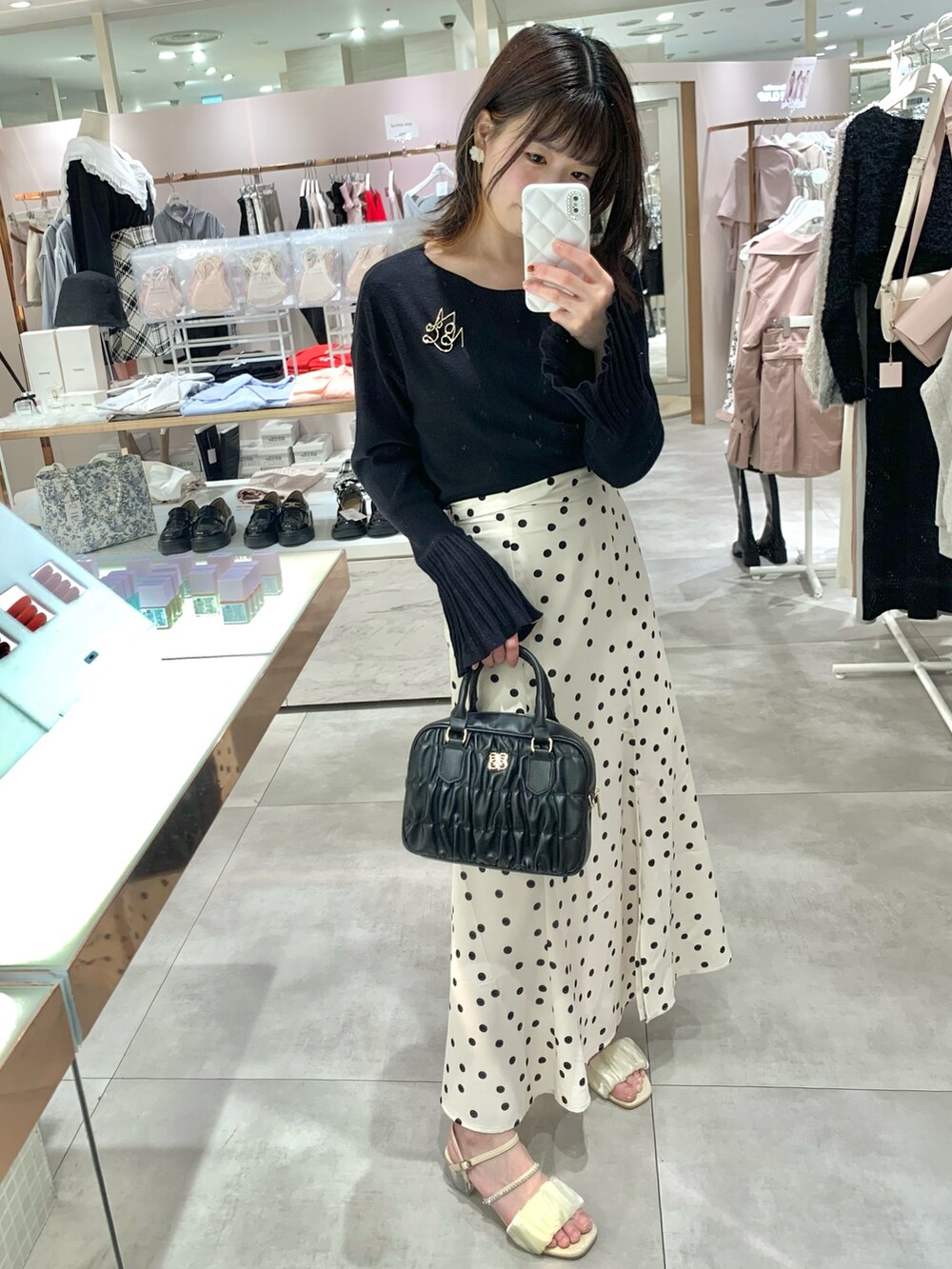 ベージュ系のトレンチコート、ホワイト系のニット/セーター、グリーン系のスカートを着用したレディースの春コーディネートの3枚目の写真