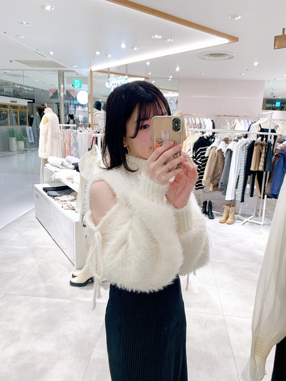 ホワイト系のニット/セーター、ブラック系のスカート、ブラック系のブーツを着用したレディースの冬コーディネートの2枚目の写真