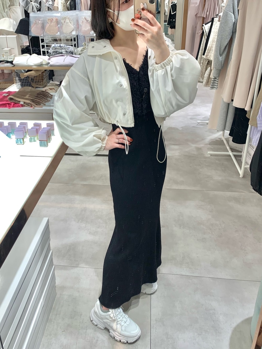 ホワイト系のマウンテンパーカー、ブラック系のワンピース、ホワイト系のスニーカーを着用したレディースの春コーディネートの2枚目の写真