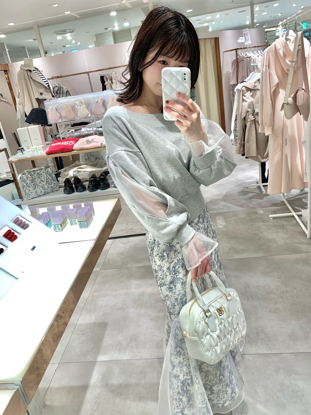 グレー系のスウェット、ホワイト系のボストンバッグ、ブルー系のスカートを着用したレディースの春コーディネートの2枚目の写真