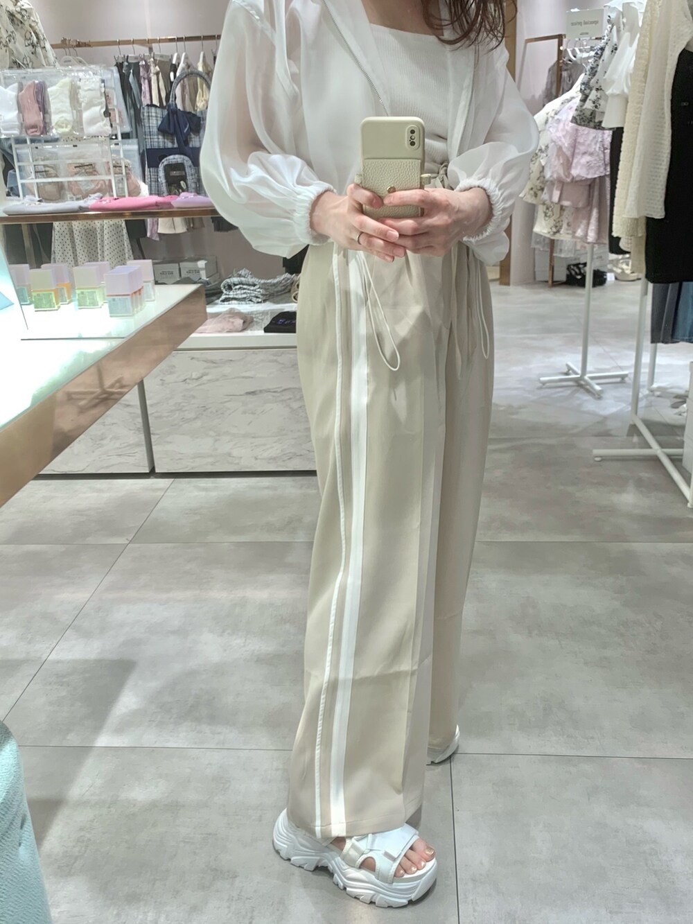 ベージュ系のスラックス、ホワイト系のサンダル、ホワイト系のマウンテンパーカーを着用したレディースの春コーディネートの2枚目の写真