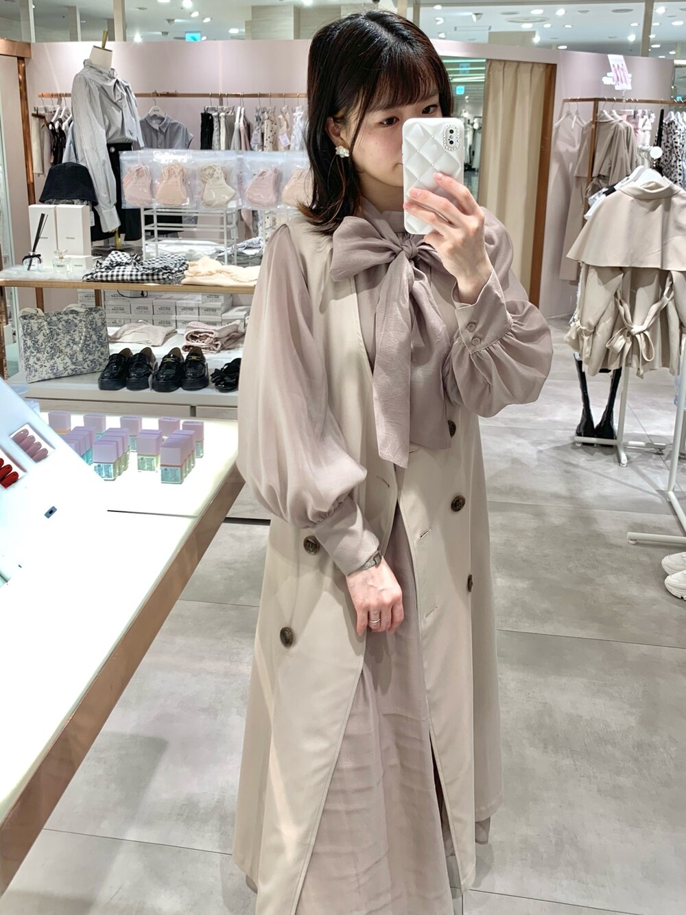 ベージュ系のトレンチコート、ホワイト系のサンダル、ホワイト系のボディバッグ/ウエストポーチを着用したレディースの春コーディネートの4枚目の写真