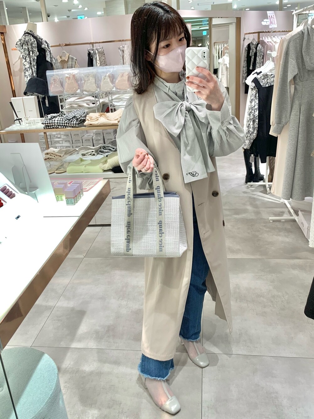 ベージュ系のトレンチコート、グレー系のブーツ、ブルー系のデニムパンツを着用したレディースの春コーディネートの4枚目の写真