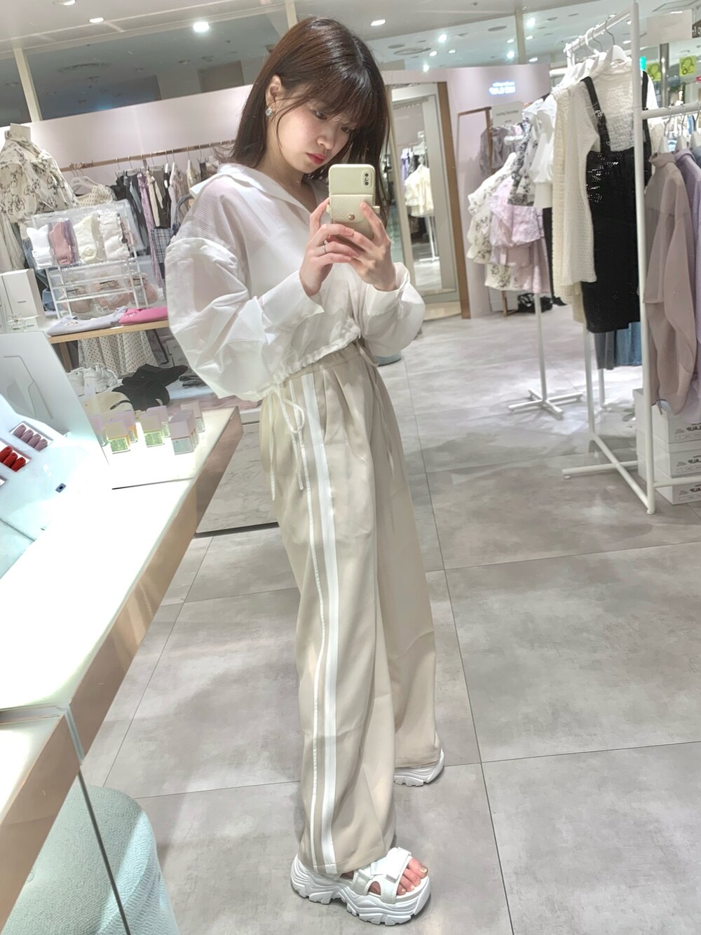 ベージュ系のスラックス、ホワイト系のサンダル、ホワイト系のマウンテンパーカーを着用したレディースの春コーディネートの9枚目の写真