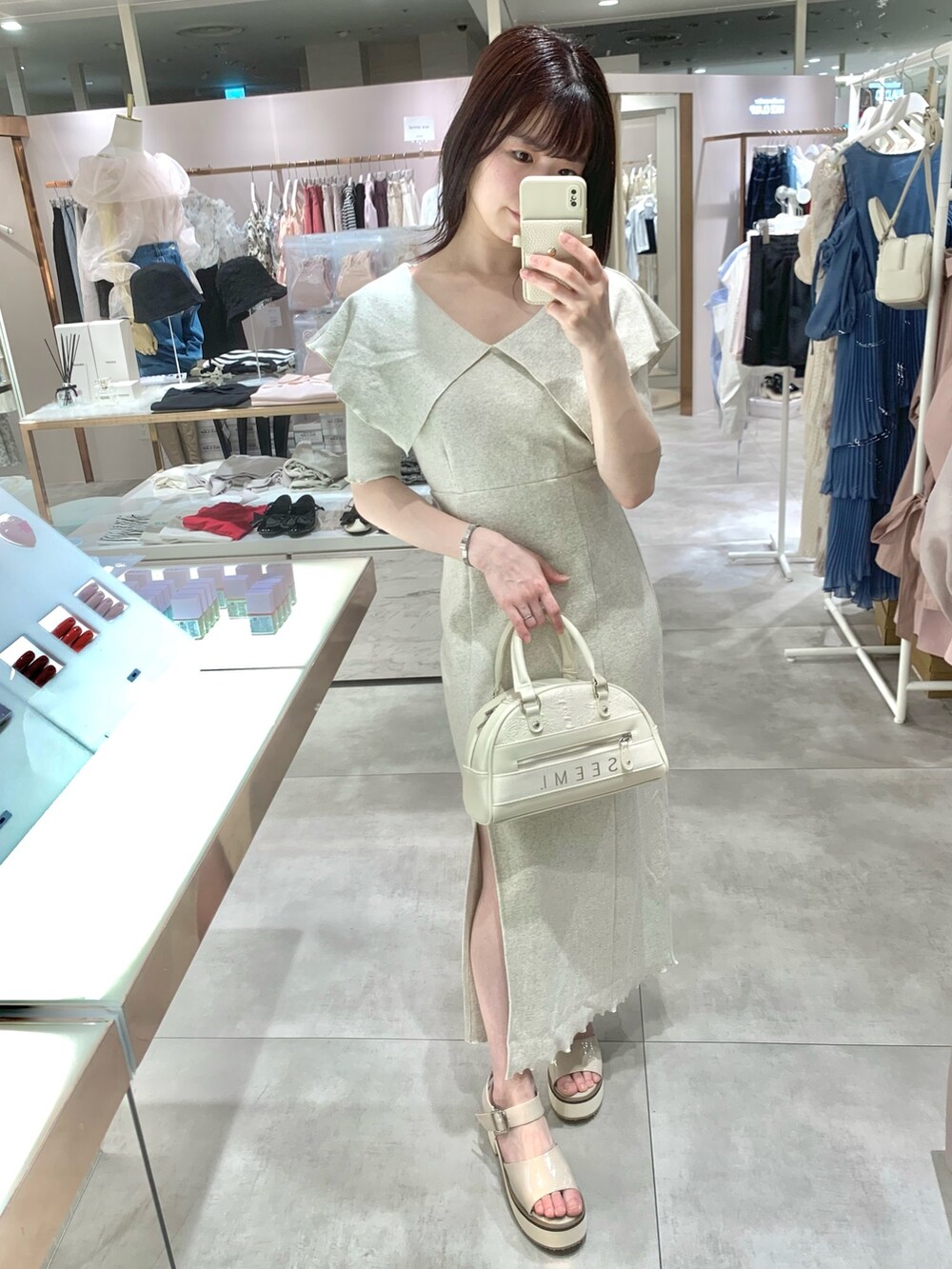 ベージュ系のワンピース、ホワイト系のボストンバッグ、ベージュ系のサンダルを着用したレディースの春コーディネートの2枚目の写真