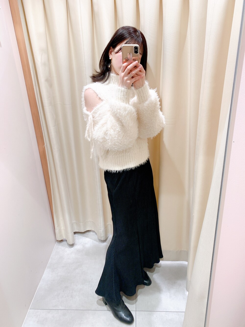 ホワイト系のニット/セーター、ブラック系のスカート、ブラック系のブーツを着用したレディースの冬コーディネートの4枚目の写真