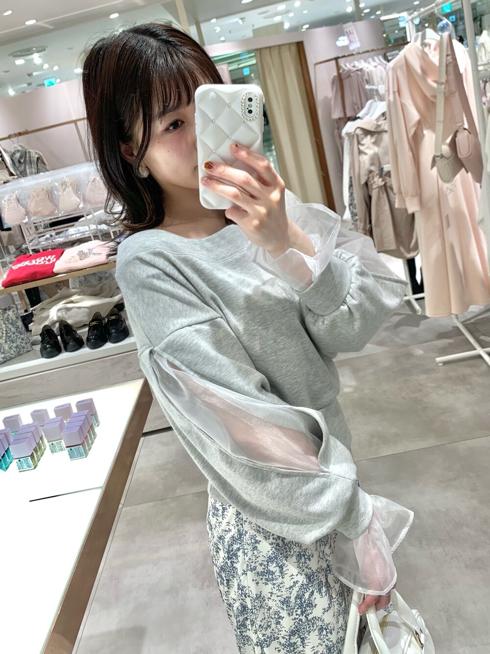 グレー系のスウェット、ホワイト系のボストンバッグ、ブルー系のスカートを着用したレディースの春コーディネートの3枚目の写真