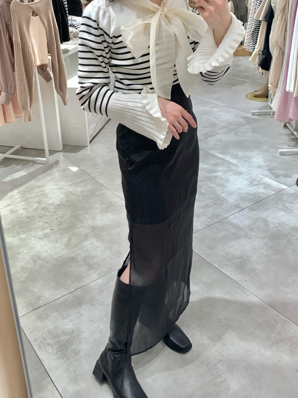 ブラック系のニット/セーター、ブラック系のスカート、ホワイト系のショルダーバッグを着用したレディースの冬コーディネートの4枚目の写真