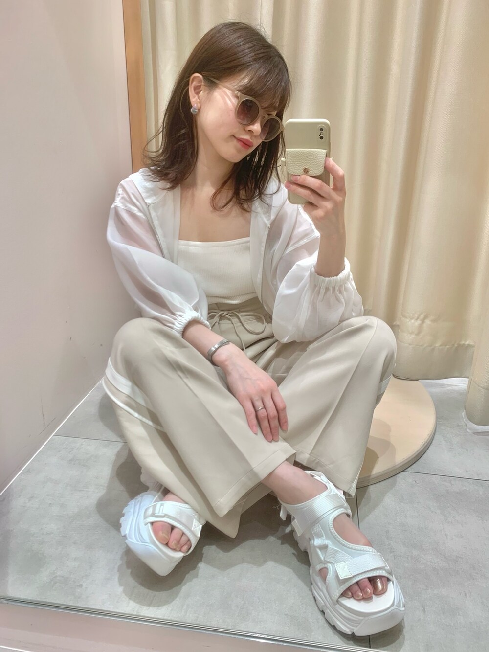 ベージュ系のスラックス、ホワイト系のサンダル、ホワイト系のマウンテンパーカーを着用したレディースの春コーディネートの4枚目の写真