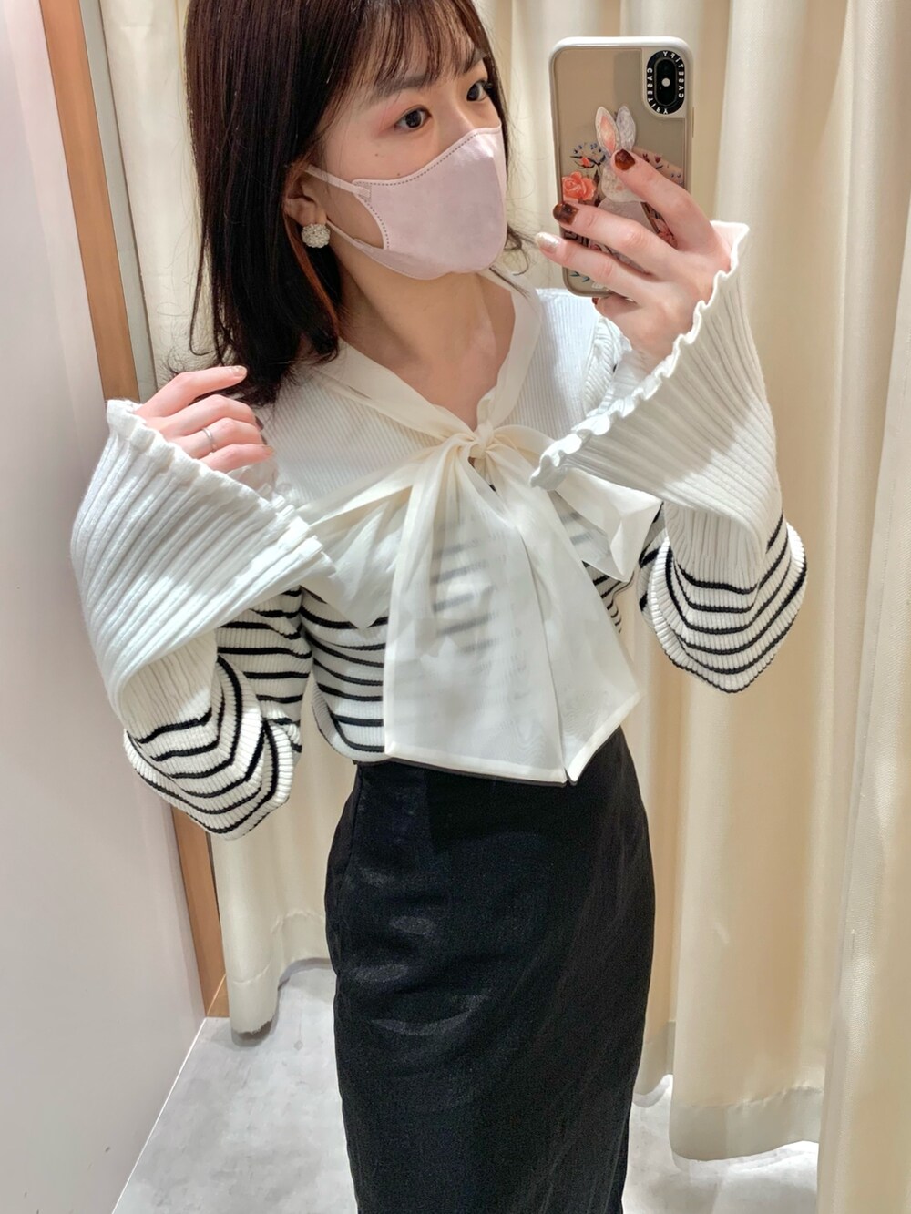 ブラック系のニット/セーター、ブラック系のスカート、ホワイト系のショルダーバッグを着用したレディースの冬コーディネートの2枚目の写真