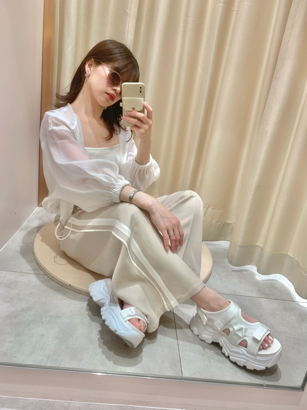 ベージュ系のスラックス、ホワイト系のサンダル、ホワイト系のマウンテンパーカーを着用したレディースの春コーディネートの3枚目の写真