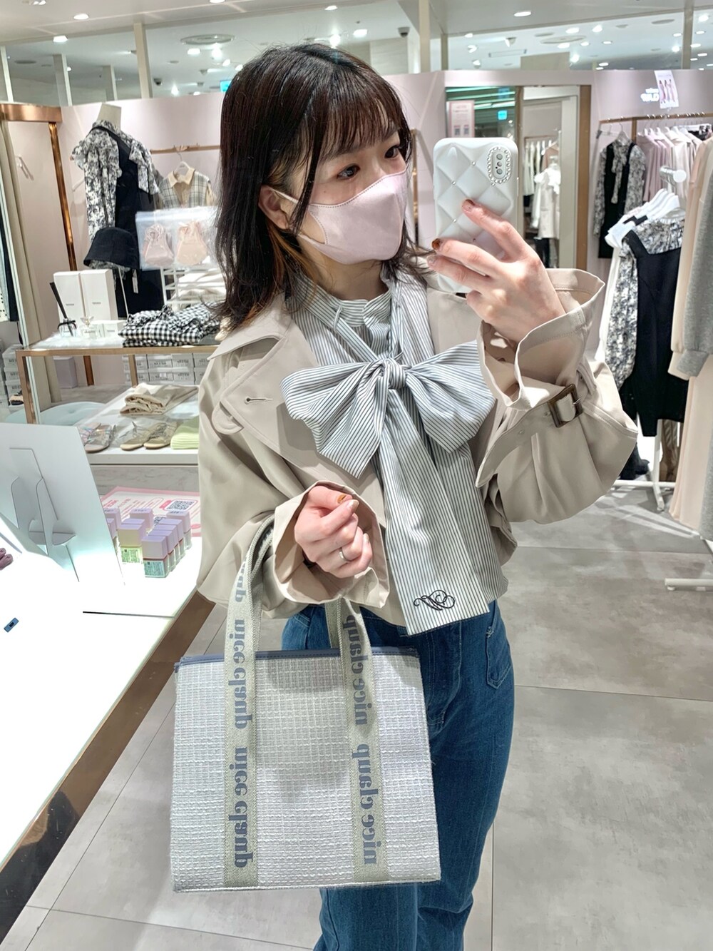 ベージュ系のトレンチコート、グレー系のブーツ、ブルー系のデニムパンツを着用したレディースの春コーディネートの3枚目の写真